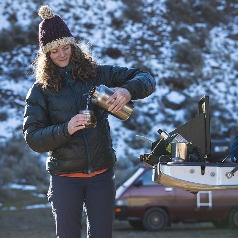 Person outdoors in winter attire, pouring from a 64oz wide mouth water bottle.