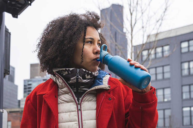 Young woman drinking from water bottle in city