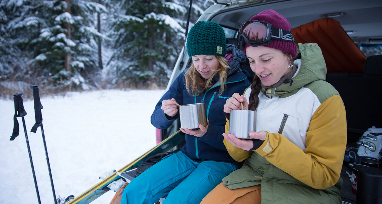 Skiiers on tailgate eating from food canisters