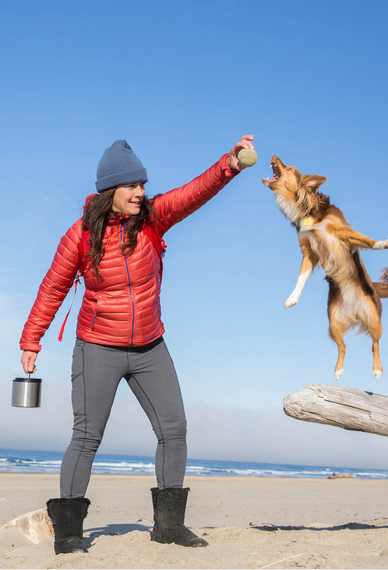 Woman on beach with dog and food canister