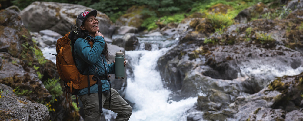Backpacker with water bottle by water fall