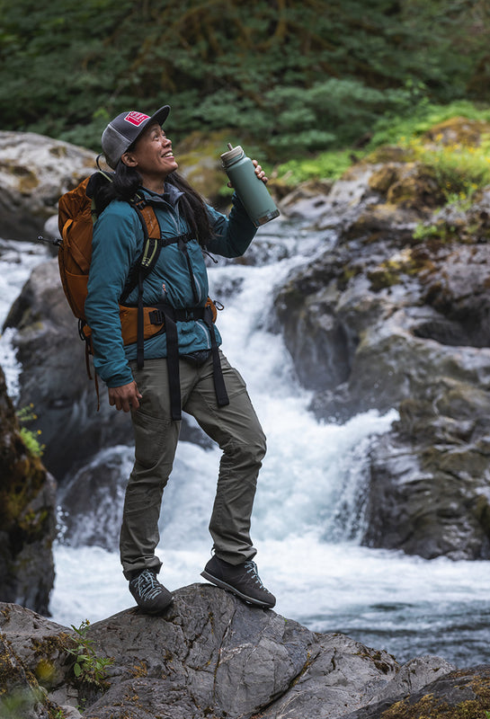 Backpacker with water bottle by water fall