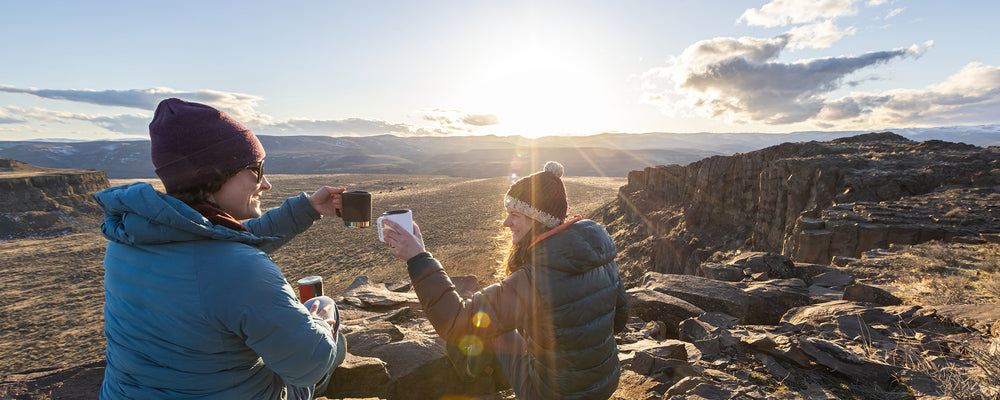 Two women drinking coffee at sunrise