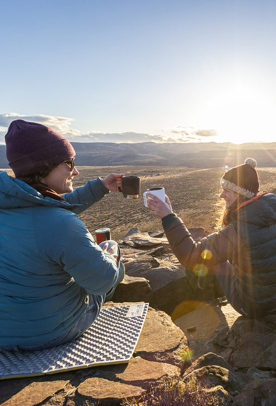 Two women drinking coffee at sunrise