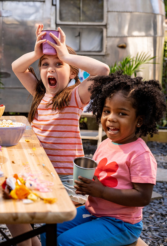 Kids playing and drinking from cups at picnic table