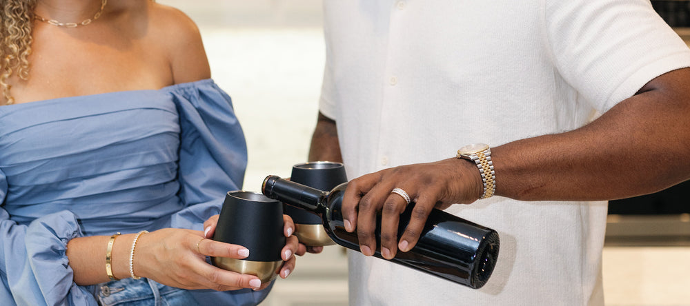 Pouring wine into black and gold wine tumbler