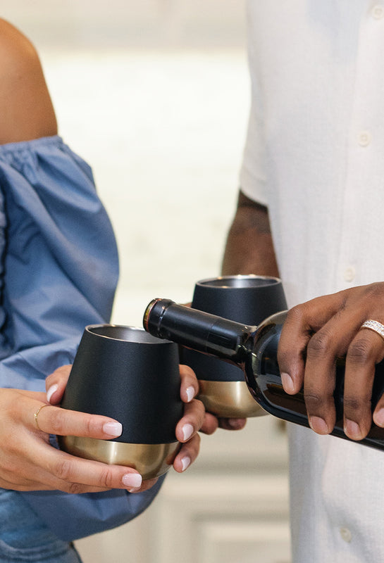 Pouring wine into black and gold wine tumbler