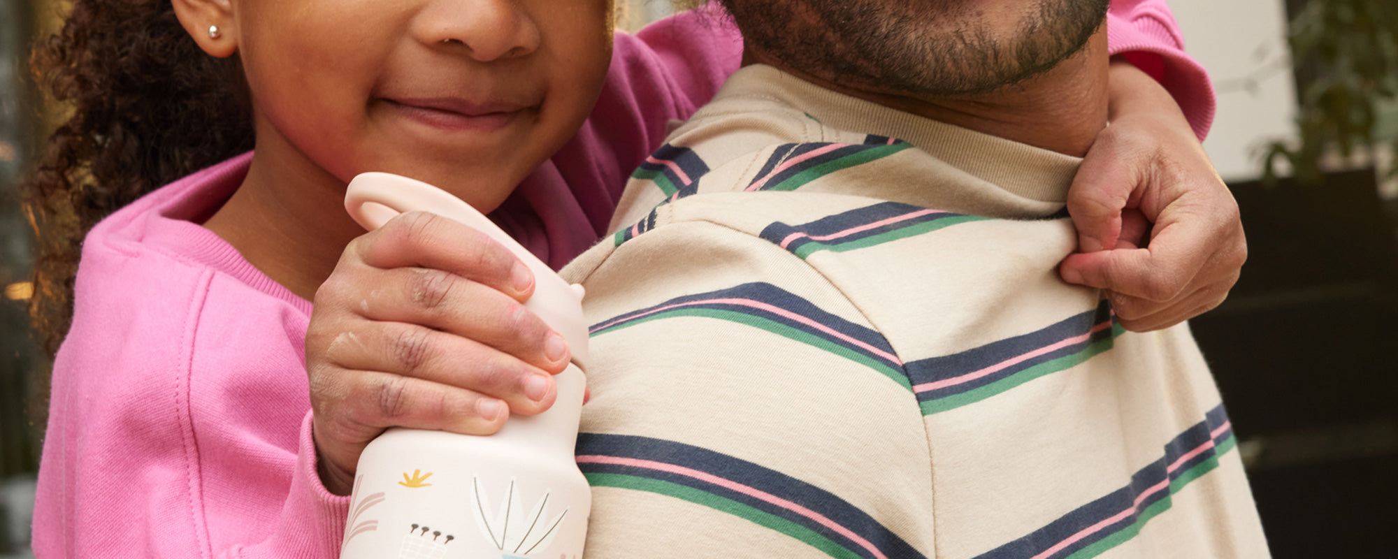Kid holding sippy bottle in hand on Dad's back