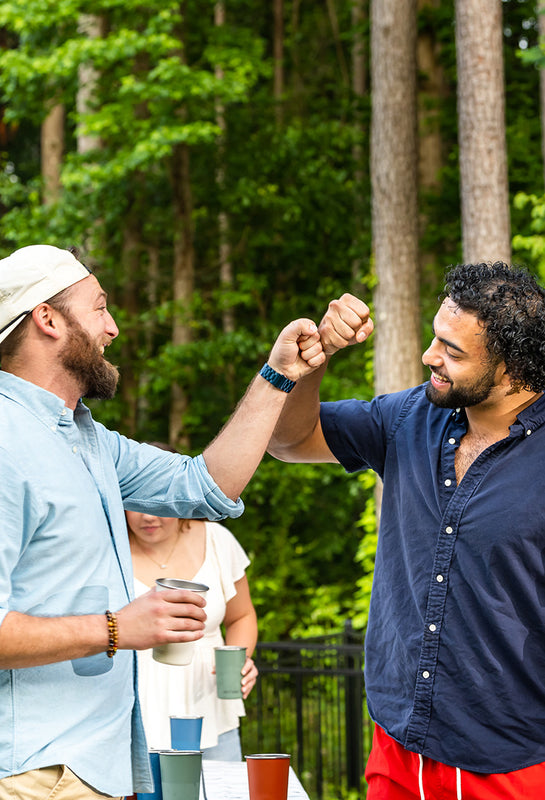 Guys playing beer pong and fist bumping