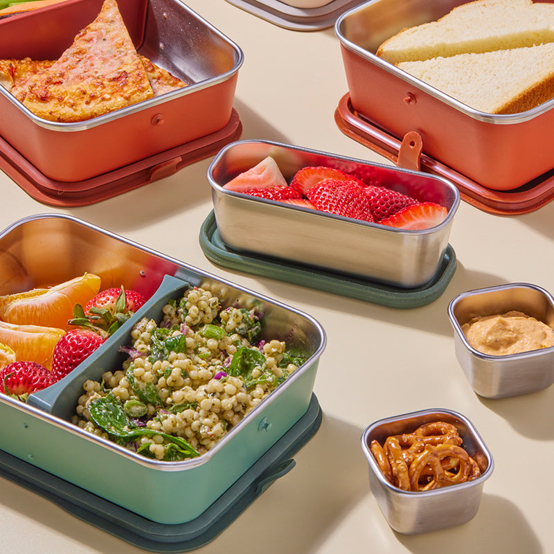 Collection of lunch containers with various food items on a table