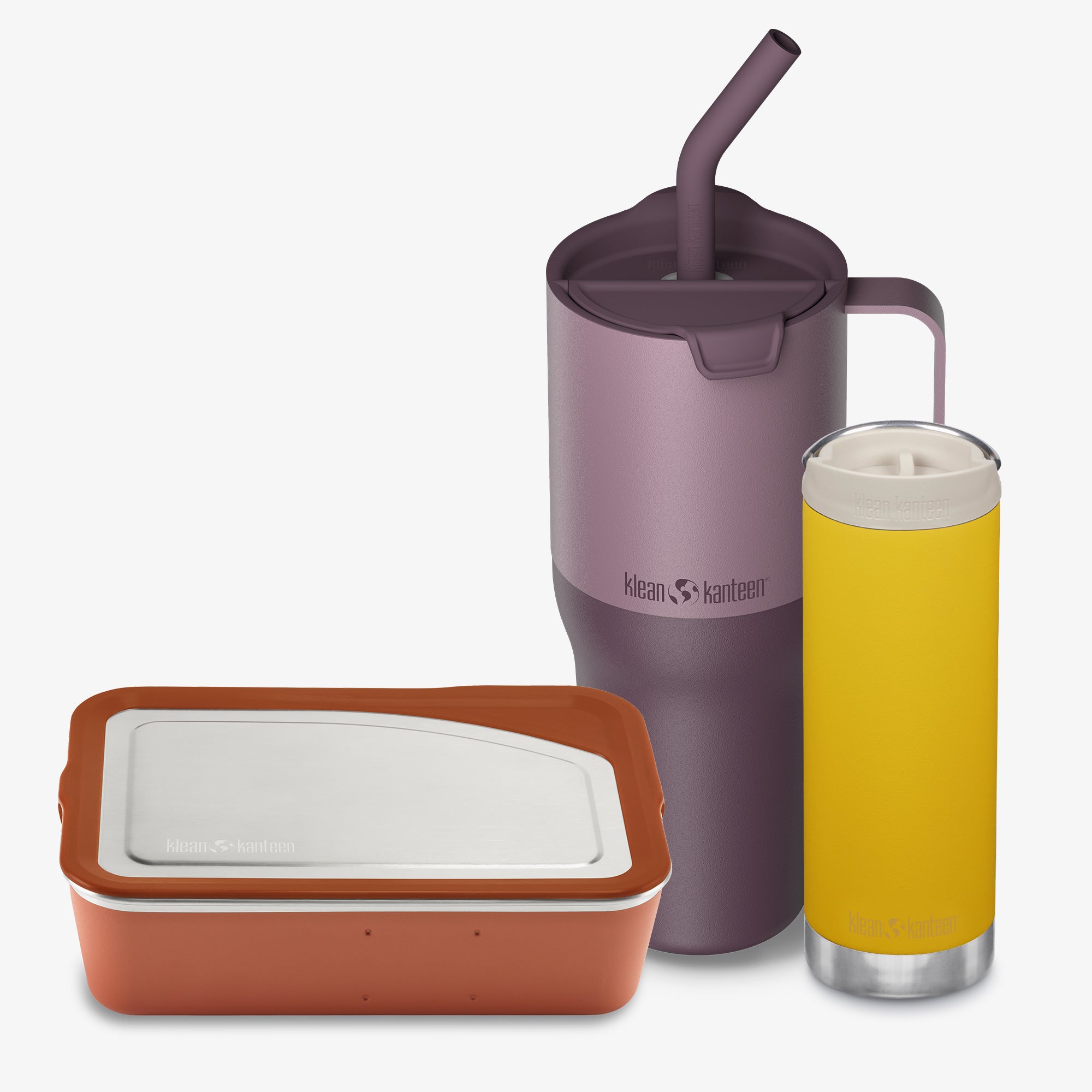 Purple tumbler with straw, brown container, and yellow glass with a white drink on a white background