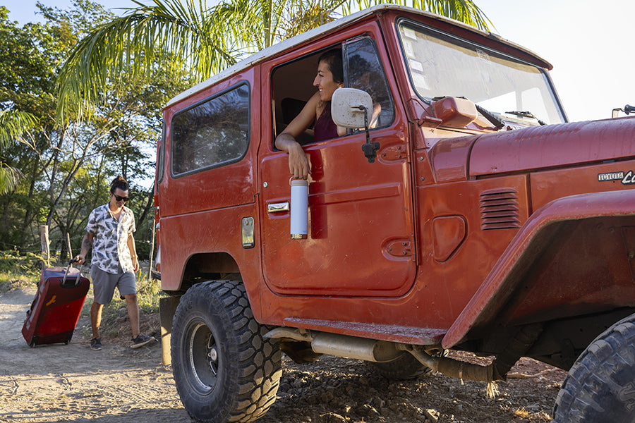 Woman looking out of jeep with water bottle
