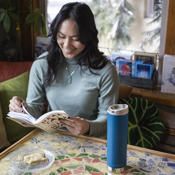 Woman with coffee tumbler reading